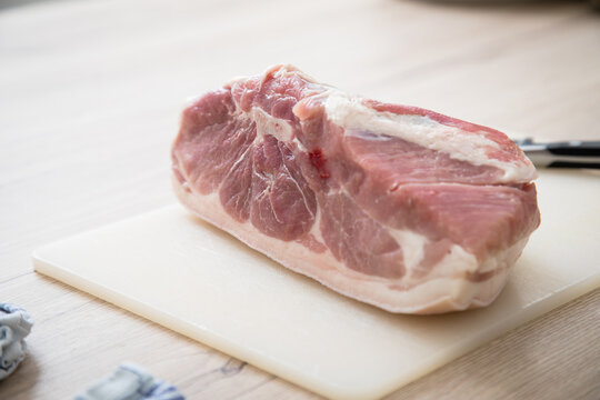 Frisch St&uuml;ck Schweinefleisch Schulter mit Knochen und Fett Scharte roh auf Plastik Schneidebrett und Messer in K&uuml;che