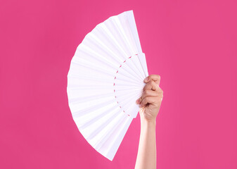 Fototapeta Woman holding white hand fan on pink background, closeup obraz