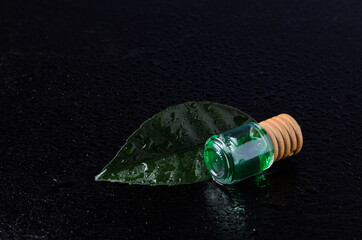Lemon flavor of emerald color in a glass bottle with a wooden stopper on a green leaf with water...