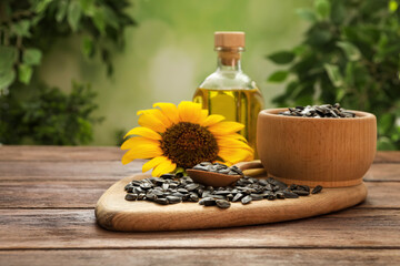 Sunflower, seeds and bottle of oil on wooden table against blurred background