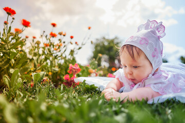Little girl baby on the flower meadow of the church garden. Baby baptism.