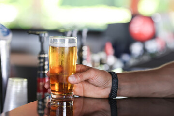 Man's hand holds glass of beer on bar. All inclusive in hotels in concept resorts