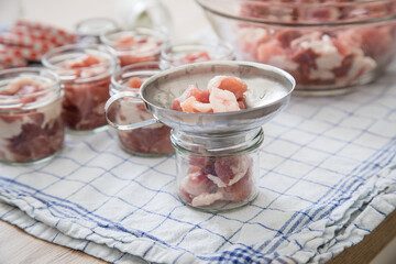 Schulter Fleisch roh in Schraubglas und Trichter zum selbstgemacht Einkochen Einwecken für Russisch Tuschonka Schweinefleisch im eigenen Saft in Küche