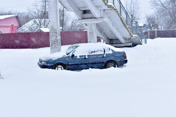 A car is parked in the snow-covered parking lot.