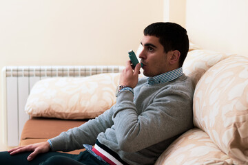Fototapeta premium young asthmatic taking a bronchodilator because he can't breathe due to coronavirus