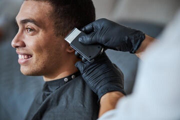 Barber hand in medicine gloves making new styling for client in beauty salon