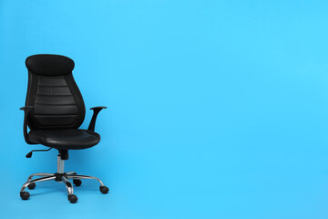 Comfortable office chair on light blue background, space for text