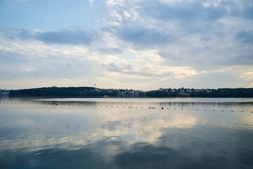 Amazing lake landscape in the evening. Blue yellow cloudy sky with reflection in water at sunset. Nature protection concept. Rural scene in countryside. Ecological conservation.Eco tourism development