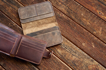 Handmade wallet made of genuine leather on a wooden background. Close-up, top view.