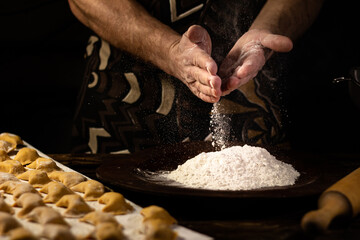 Strong men's hands sprinkle flour dumplings. Ukrainian national dish.