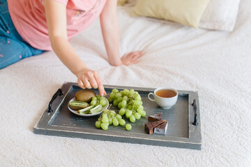 Obraz na płótnie Canvas Wooden tray with tea and fruits Healthy breakfast in bed. Soft focus. Background.