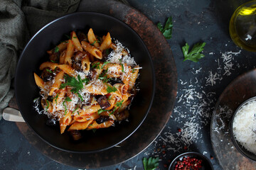 Pasta alla norma - Italian pasta with eggplant, tomato and parmesan cheese on dark table. Top view with copy space.