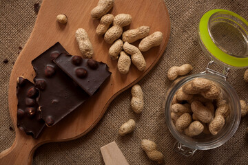 Chocolate and peanuts on a wooden board on a burlap background.