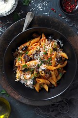 Pasta alla norma - Italian pasta with eggplant, tomato and parmesan cheese on dark table. Top view with copy space.