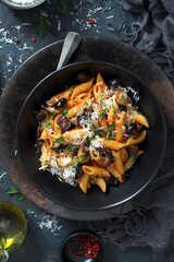 Pasta alla norma - Italian pasta with eggplant, tomato and parmesan cheese on dark table. Top view with copy space.