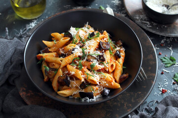 Pasta alla norma - Italian pasta with eggplant, tomato and parmesan cheese on dark table. Top view with copy space.