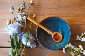 Porcelain set on a wooden table. Wooden spoon in a blue plate. Blue plate with flowers
