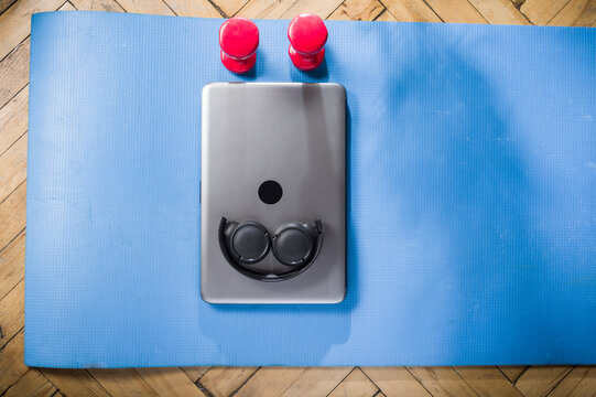 Laptop and headphones. Fitness mat and dumbbells.