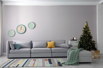 Light living room interior with Christmas tree and large sofa