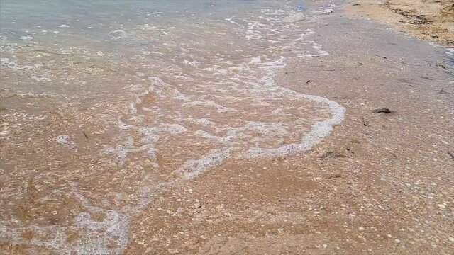 A woman draws a heart on the seashore which is washed away by a wave. The wave washes away the heart nestled in the sand. Woman draws a heart in the sand