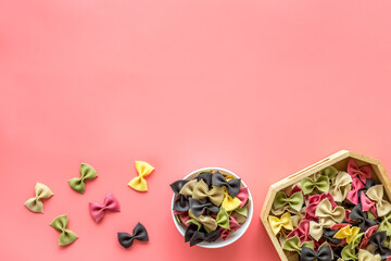 Obraz na płótnie Canvas Italian farfalle pasta in bowls. Raw multicolored farfalle pasta, overhead view