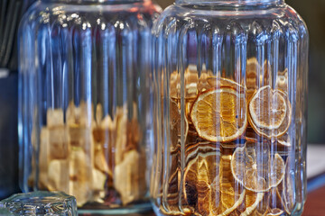Dried oranges in a transparent glass jar on a bar table.
