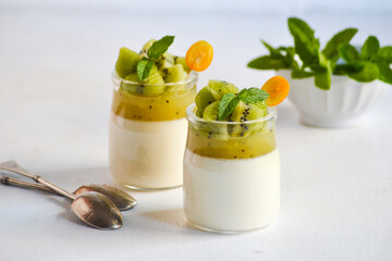 Italian dessert panna cotta in glass jars with kiwi fruit jelly decorated with pieces of fresh kiwi...