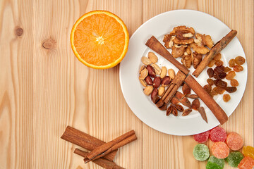 Still life of orange, candied fruits, nuts, cinnamon sticks, raisins on a wooden background. Close-up. top view.