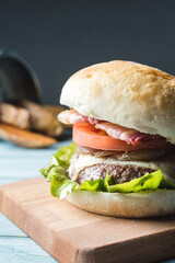 Bacon, cheese, tomato, onion and lettuce burguer with fried potatoes at back