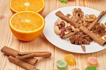 Still life of dried fruits, nuts and oranges on a wooden table top.