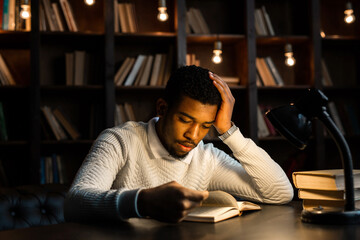 handsome young african man on sofa on background of books 