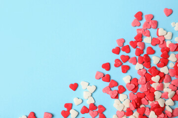 Bright heart shaped sprinkles on light blue background, flat lay. Space for text