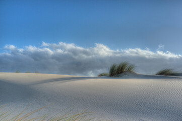 White sand dune with Ammophila grass against blue sky with Stratus clouds at famous Tarifa coast