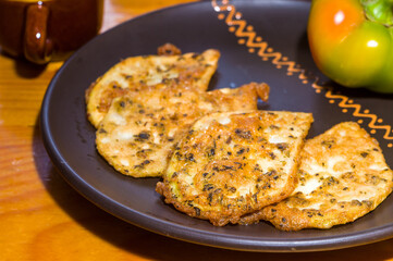 Vegetarian food - celery tuber slices fried in batter in a ceramic plate on a wooden table, close up