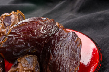 Big luxury dried date fruit in bowls on the dark surface, kurma ramadan kareem concept, close up.