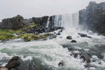Oksararfoss Falls in Tingvellir National Park in Iceland. cloudy weather and water dust. Epic view and look. concept of research and travel in the Scandinavian countries. Fresh air and pristine nature