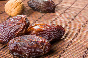 Big luxury dried date fruit on the bamboo mat, kurma ramadan kareem concept, close up.