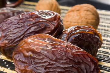 Big luxury dried date fruit on the bamboo mat, kurma ramadan kareem concept, close up.