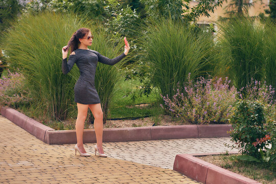 Charming brunette in sunglasses takes a selfie in the botanical garden.