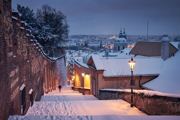 Cityscape of Prague in winter.  Lonely man (in blurred motion) walking on staircase against Lesser...
