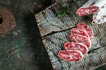 Spanish Fuet salami wurst on a wooden cutting board. Slices of spanish salami. Traditional Spanish sausage on wooden background. banner, menu, recipe, place for text Top view