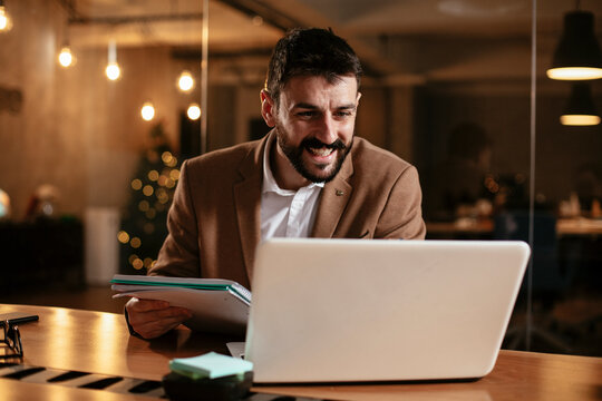Young businessman using laptop in his office. Businessman taking a notes while working on laptop.