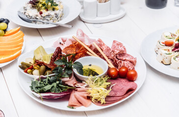 Food tray with delicious salami, pieces of sliced ham, sausage. Cutting sausage and cured meat on a celebratory table.