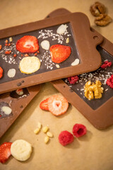 Handmade chocolate with fresh and dried fruits on light paper background in rustic style