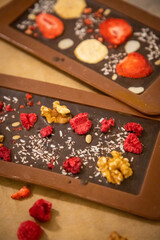 Handmade chocolate with fresh and dried fruits on light paper background in rustic style