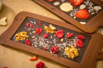 Handmade chocolate with fresh and dried fruits on light paper background in rustic style
