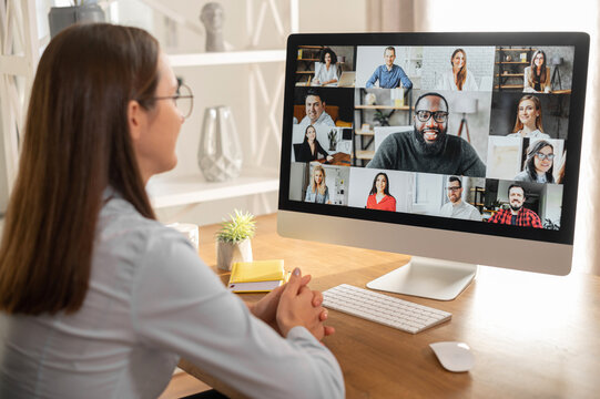 Brainstorm, Online Video Meeting, Virtual Conference With Multi Ethnic Coworkers, Employee, Colleagues. View Over Shoulder Of A Woman In Formal Shirt On A Screen With Webcam Shots Of Diverse People