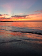 Fototapeta na wymiar Atardecer anaranjado y rosado en la orilla de una playa con mar