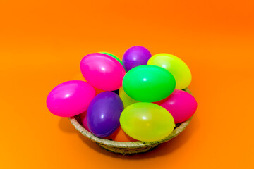 Wicker basket with colorful Easter eggs on yellow background.