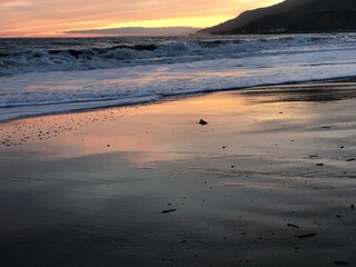 Atardecer anaranjado y rosado en la orilla de una playa de con mar